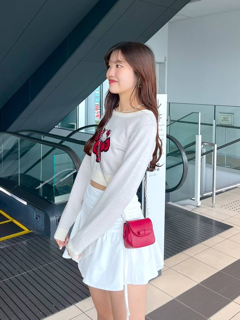 ホワイト系のTシャツ/カットソー、レッド系のショルダーバッグ、ブラック系のブーツを着用したレディースの秋コーディネートの2枚目の写真