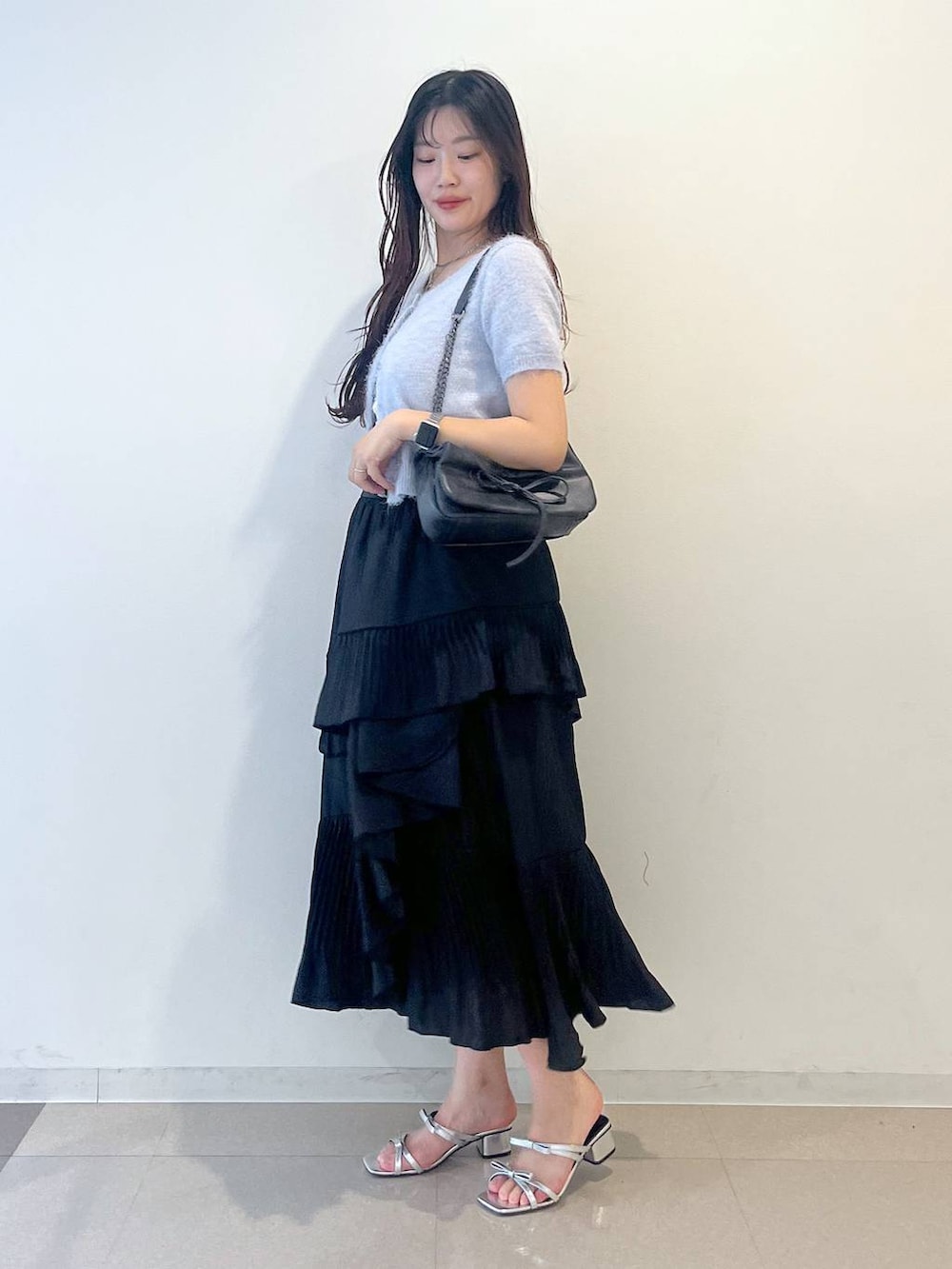 グレー系のショルダーバッグ、ブラック系のスカート、ホワイト系のキャミソールを着用したレディースの春コーディネートの3枚目の写真