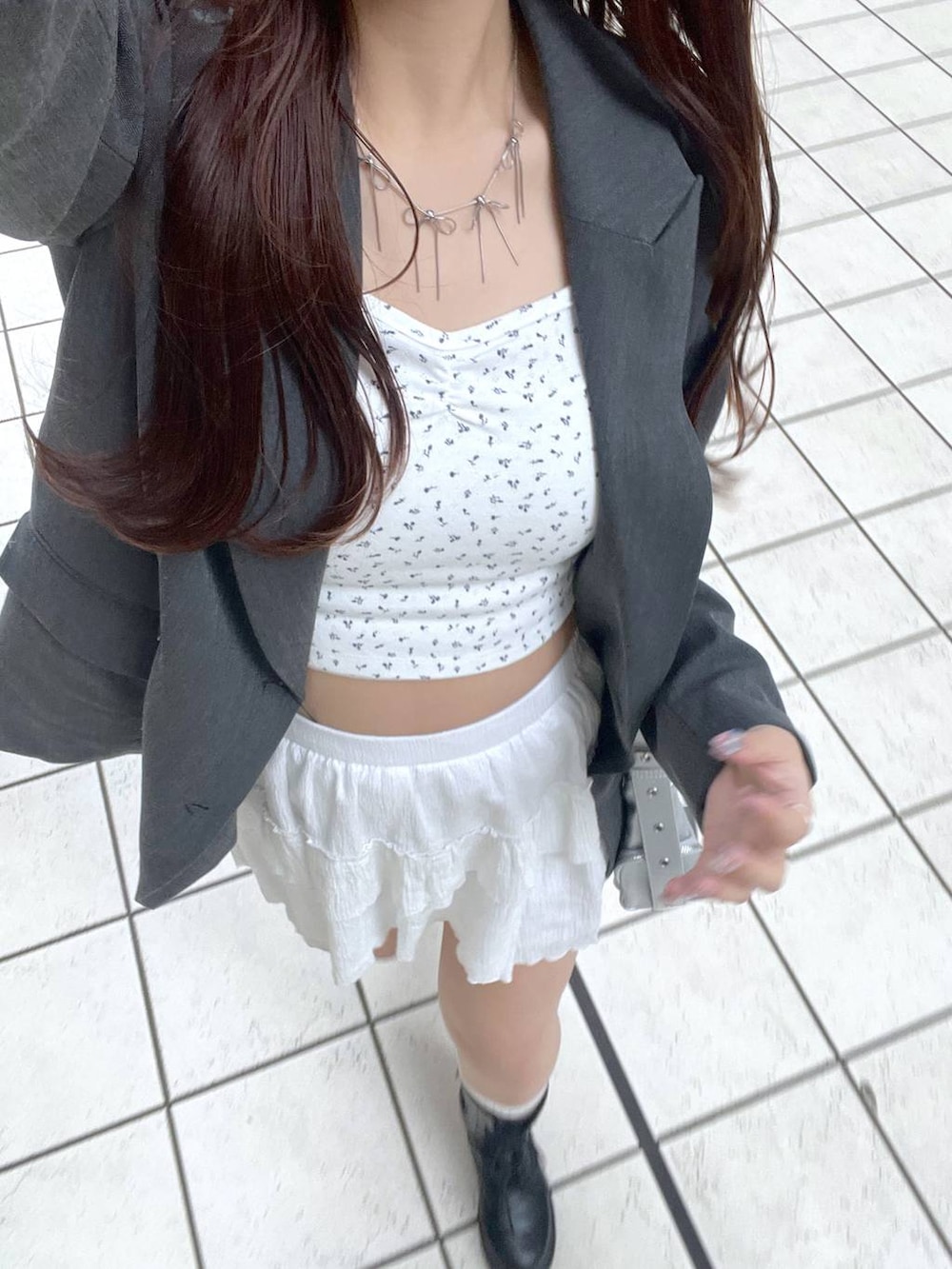 ホワイト系のキャミソール、ホワイト系のスカート、ブラック系のブーツを着用したレディースの春コーディネートの5枚目の写真