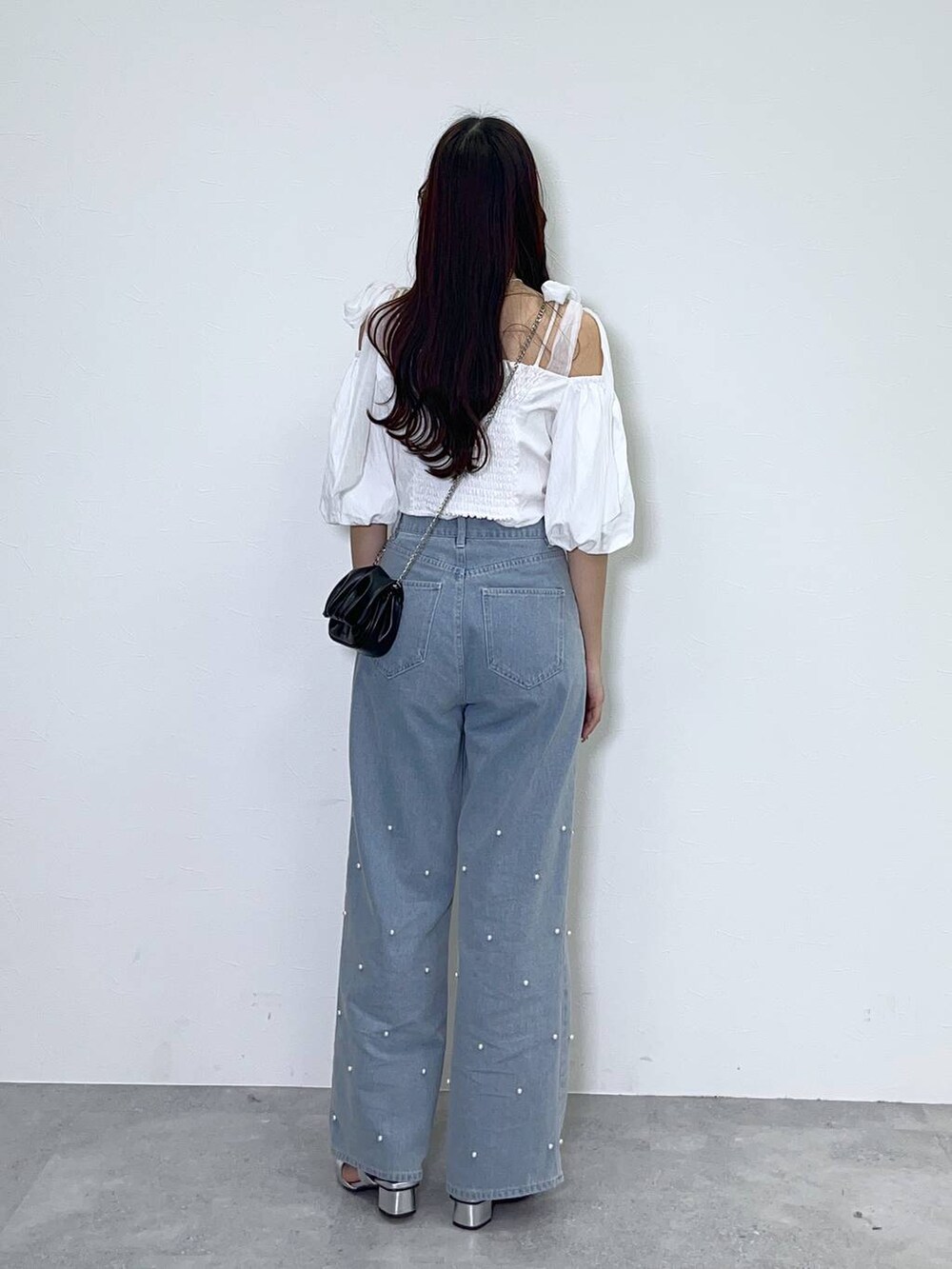 ブラック系のショルダーバッグ、ホワイト系のキャミソール、ブルー系のデニムパンツを着用したレディースの夏コーディネートの3枚目の写真