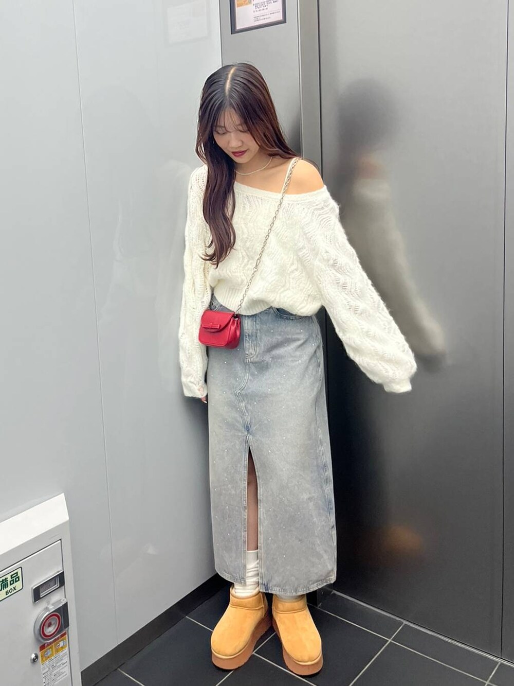 ブルー系のデニムスカート、ホワイト系のキャミソール、レッド系のショルダーバッグを着用したレディースの秋コーディネートの4枚目の写真