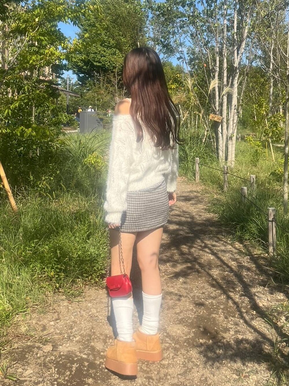 ホワイト系のニット/セーター、ホワイト系のキャミソール、ブラック系のスカートを着用したレディースの秋コーディネートの6枚目の写真