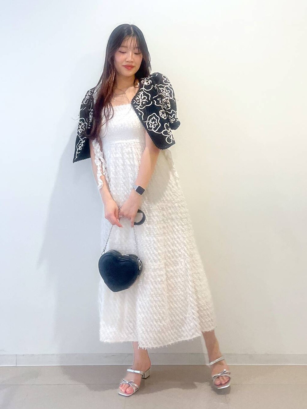 シルバー系のサンダル、ホワイト系のワンピース、ブラック系のショルダーバッグを着用したレディースの春コーディネートの5枚目の写真