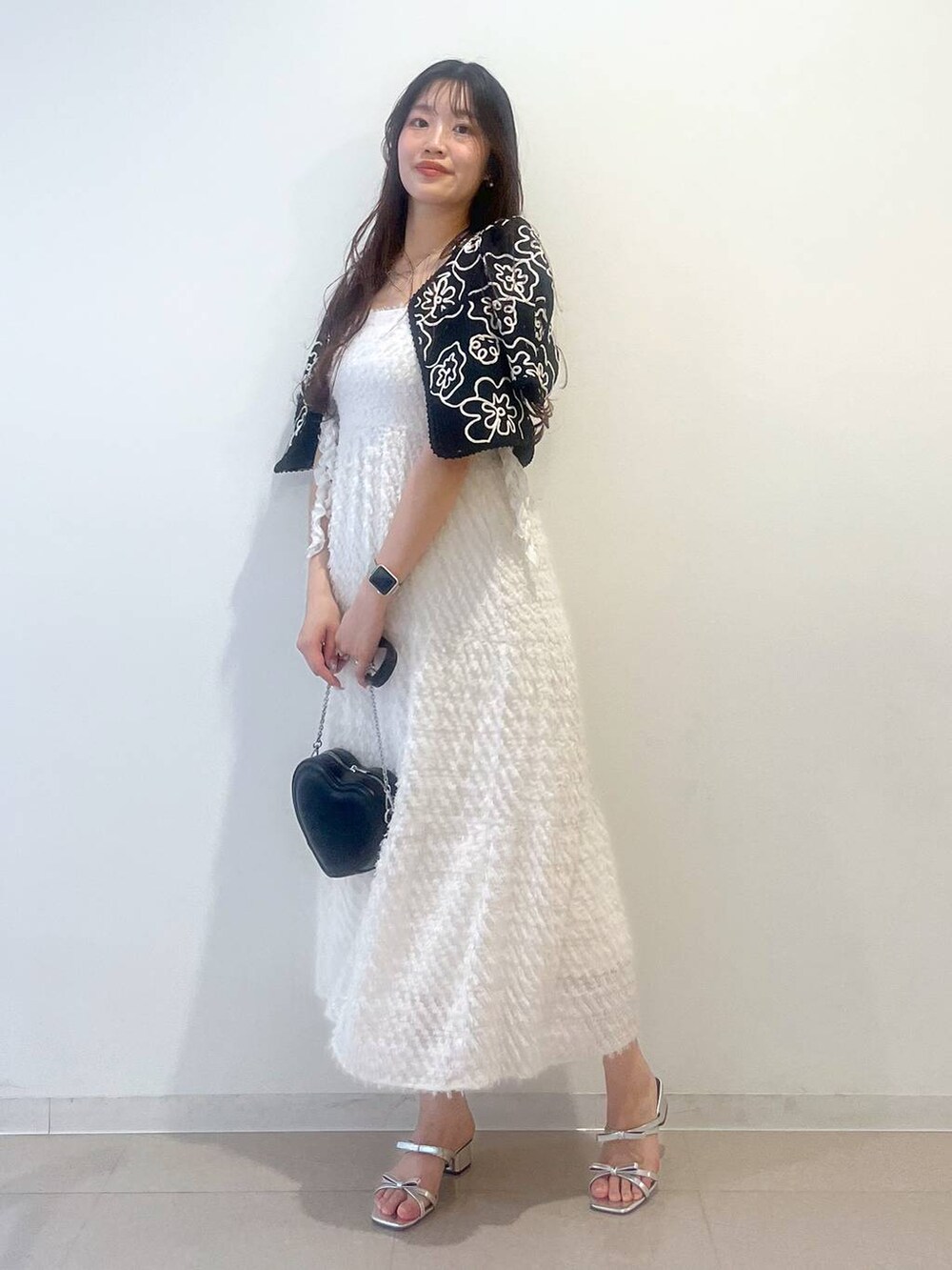 シルバー系のサンダル、ホワイト系のワンピース、ブラック系のショルダーバッグを着用したレディースの春コーディネートの6枚目の写真
