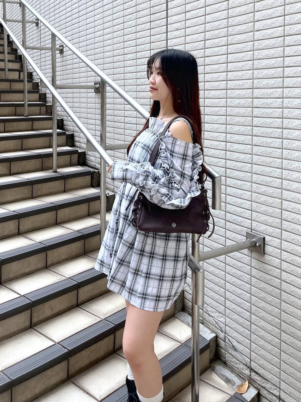 ホワイト系のキャミソール、ブラック系のデニムスカート、ブラウン系のショルダーバッグを着用したレディースの春コーディネートの6枚目の写真