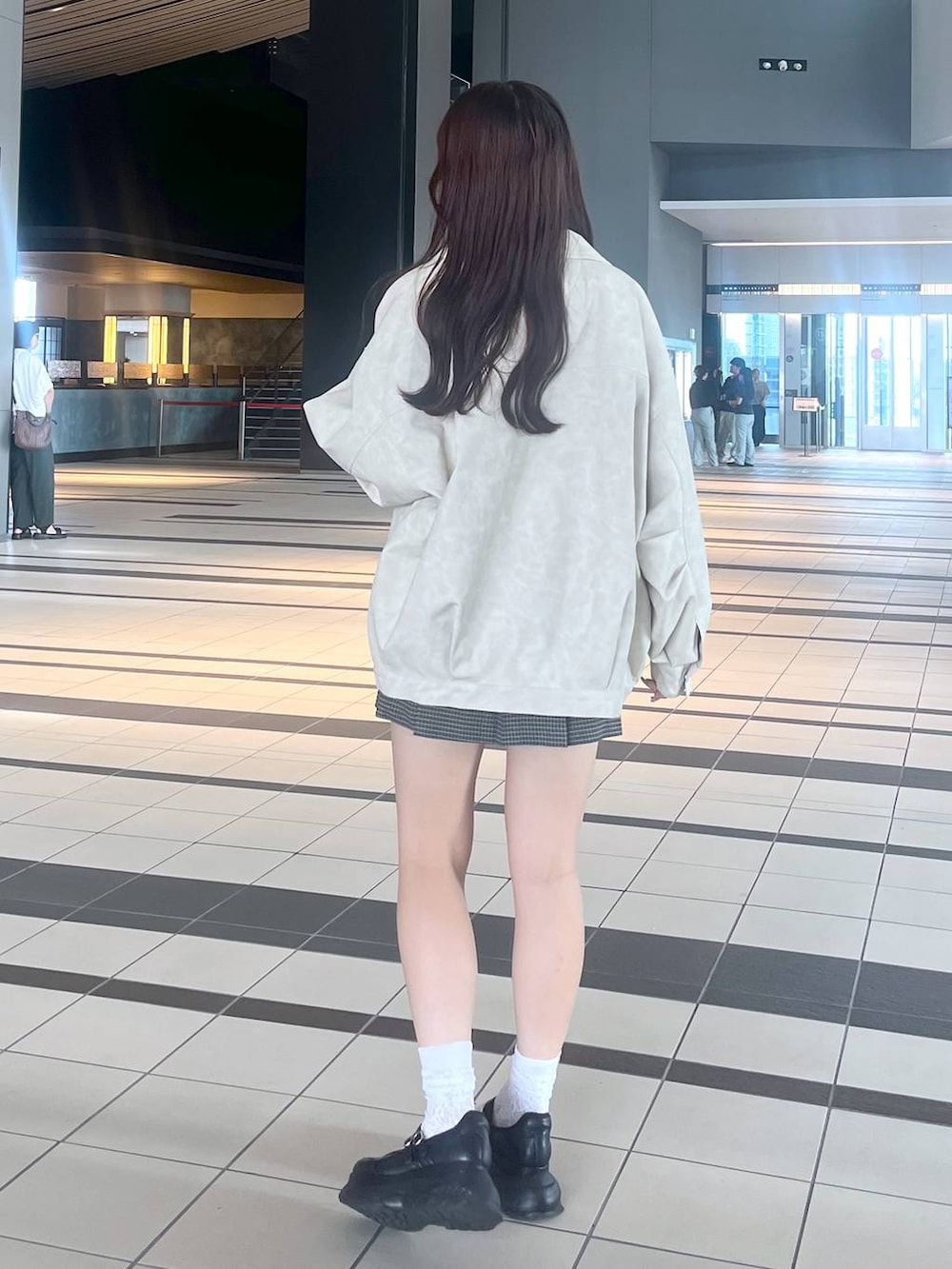 ブラック系のスニーカー、ホワイト系のキャミソール、ホワイト系のブルゾンを着用したレディースの秋コーディネートの8枚目の写真