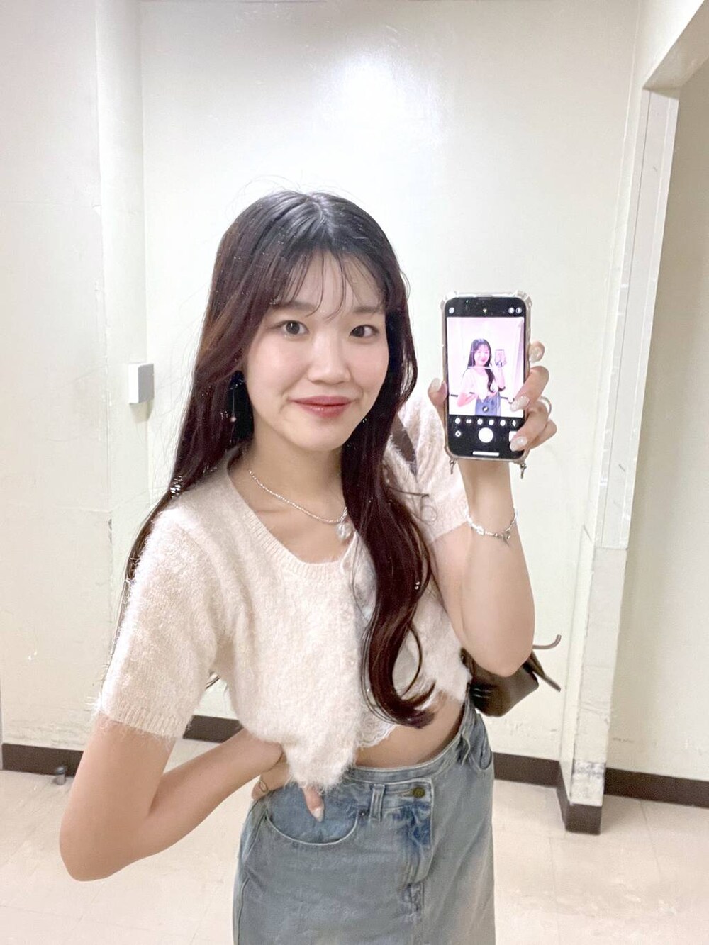 ピンク系のカーディガン/ボレロ、ブラウン系のショルダーバッグ、ホワイト系のキャミソールを着用したレディースの夏コーディネートの2枚目の写真