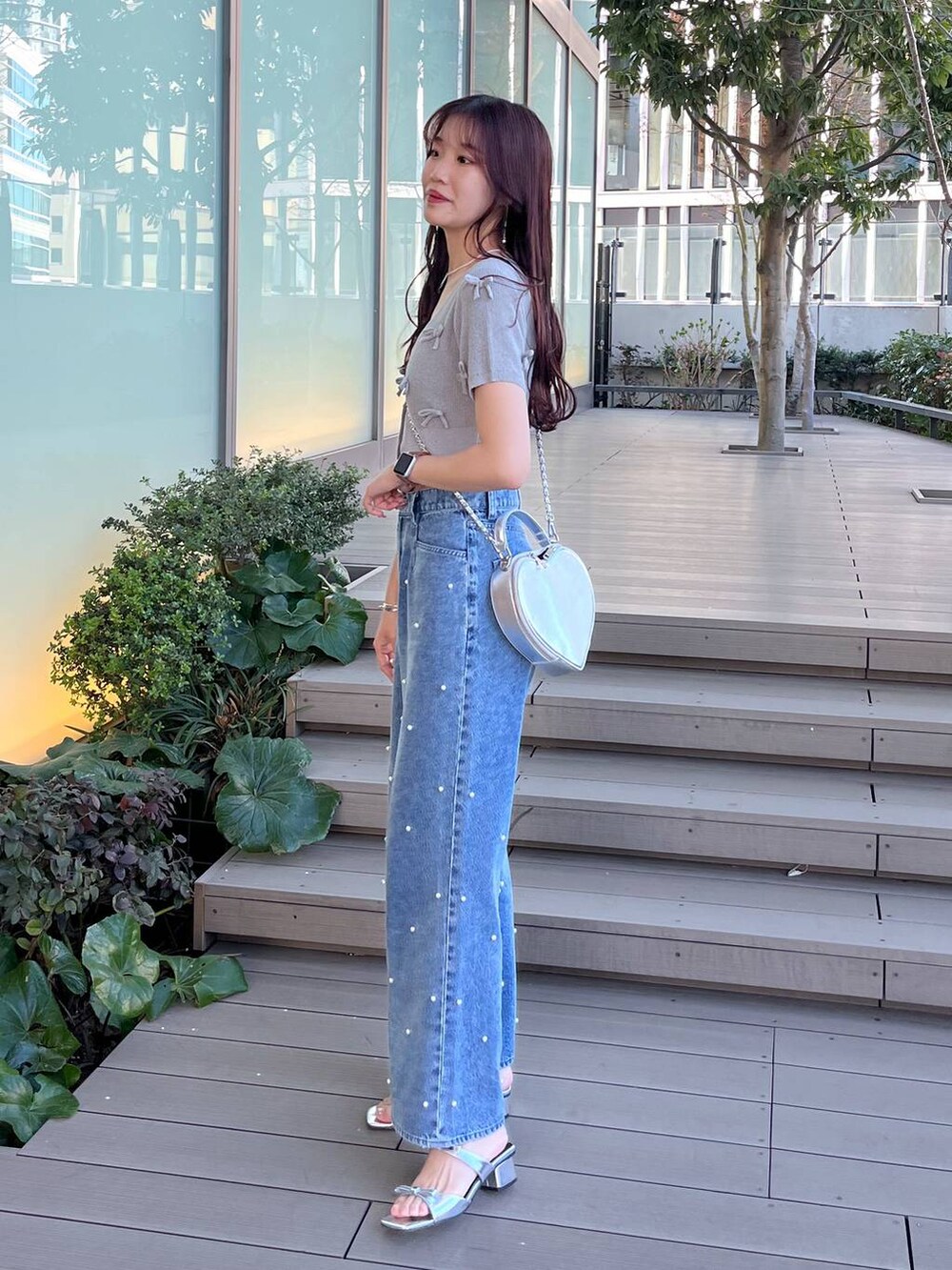 シルバー系のショルダーバッグ、ブルー系のデニムパンツ、ホワイト系のキャミソールを着用したレディースの春コーディネートの5枚目の写真