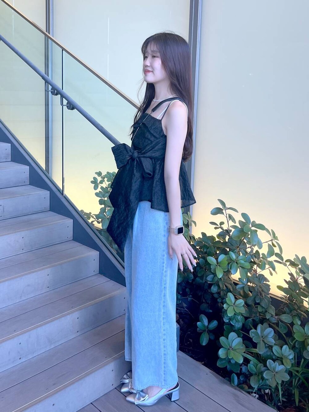 シルバー系のサンダル、ブラック系のショルダーバッグ、ホワイト系のキャミソールを着用したレディースの夏コーディネートの4枚目の写真