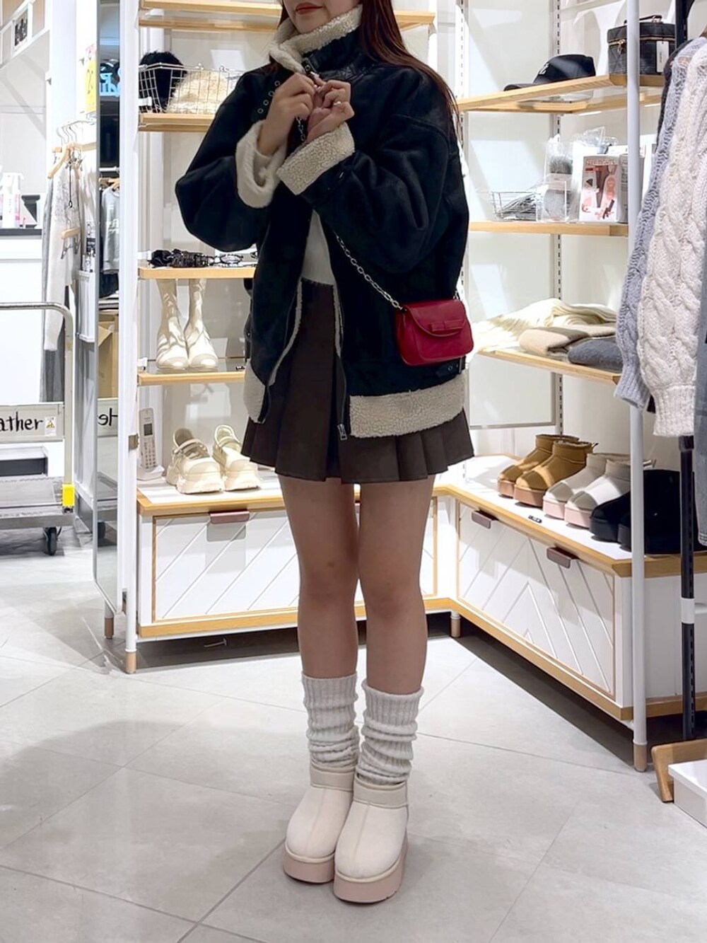 ブラウン系のスカート、ホワイト系のニット/セーター、ホワイト系のブーツを着用したレディースの冬コーディネートの2枚目の写真