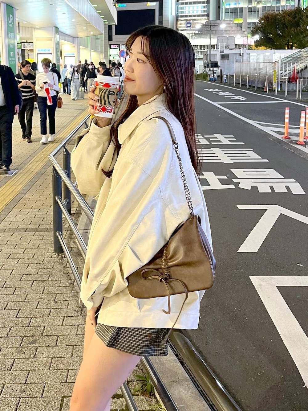 ブラウン系のショルダーバッグ、ベージュ系のスカート、ブラック系のブーツを着用したレディースの秋コーディネートの2枚目の写真