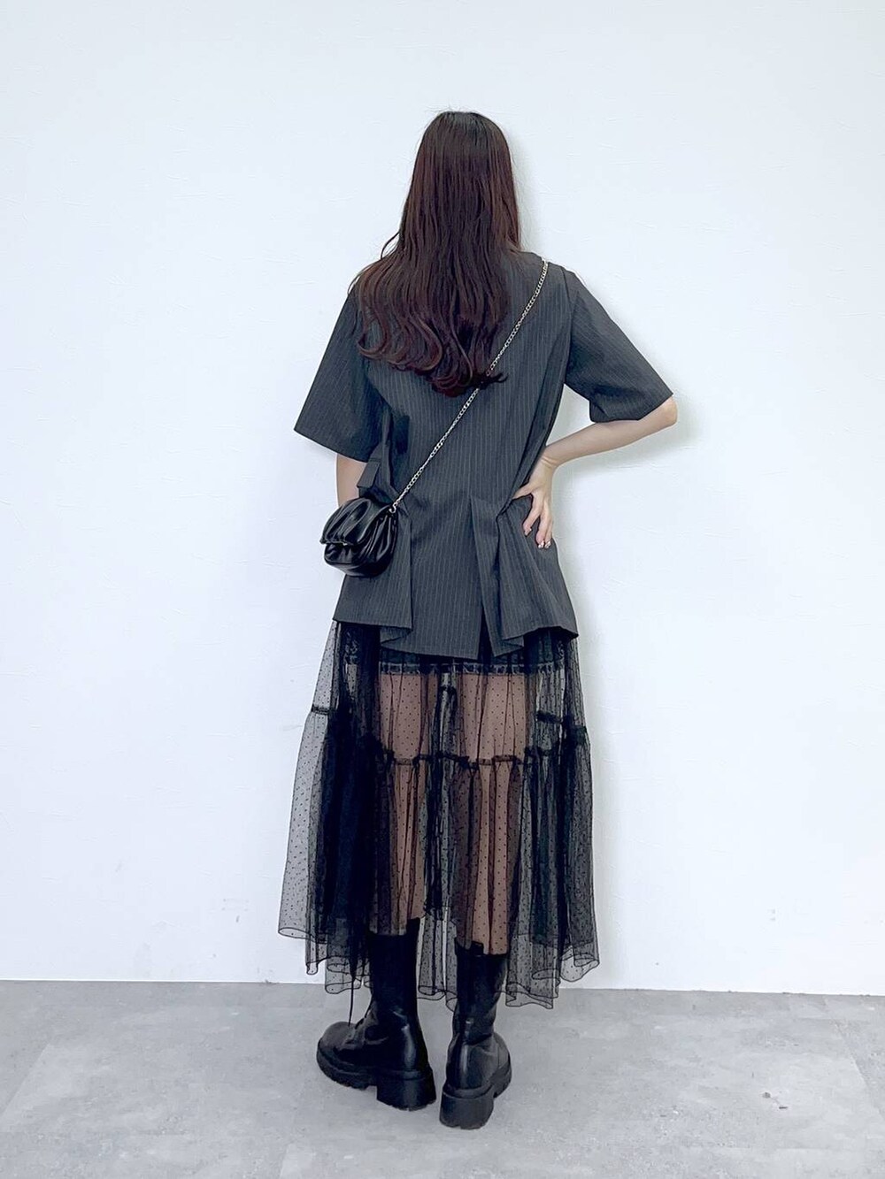 ブラック系のショルダーバッグ、ホワイト系のキャミソール、ブラック系のブーツを着用したレディースの夏コーディネートの3枚目の写真