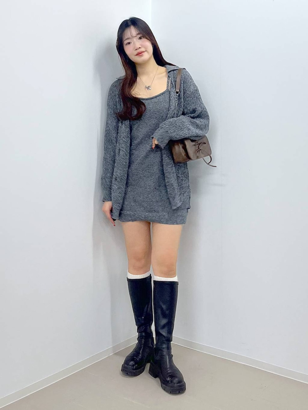 ブラウン系のショルダーバッグ、ホワイト系のキャミソール、ブラック系のブーツを着用したレディースの春コーディネートの3枚目の写真