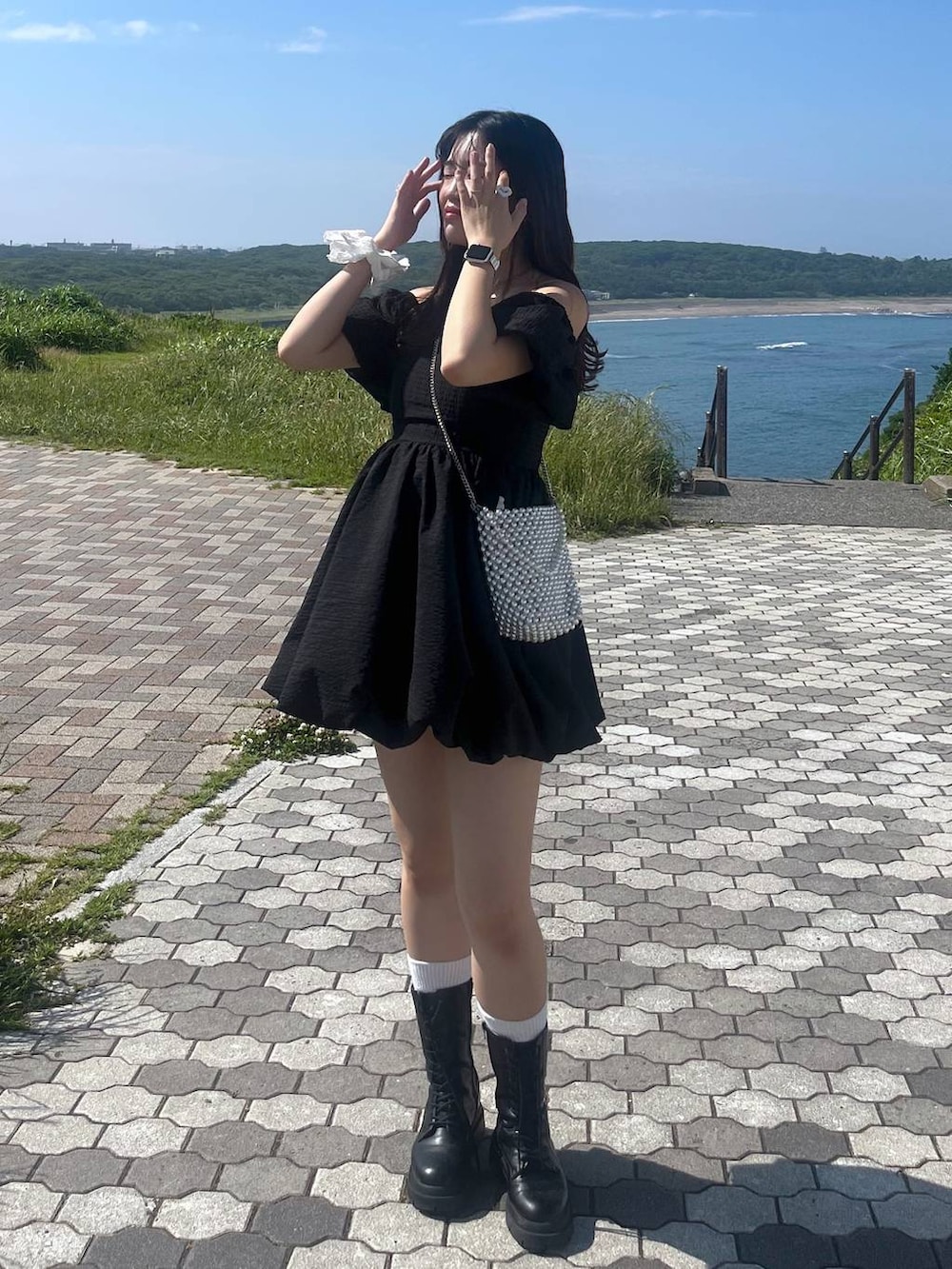 ホワイト系のキャミソール、ブラック系のワンピース、ブラック系のブーツを着用したレディースの夏コーディネートの2枚目の写真