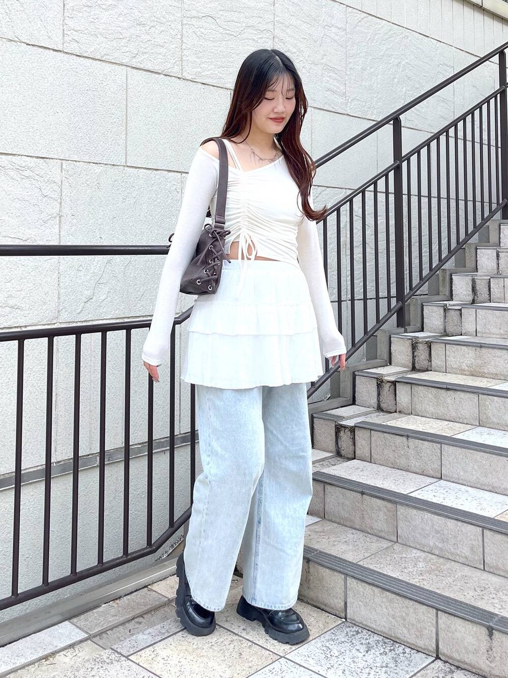 ホワイト系のキャミソール、ブルー系のデニムパンツ、ホワイト系のスカートを着用したレディースの春コーディネートの3枚目の写真