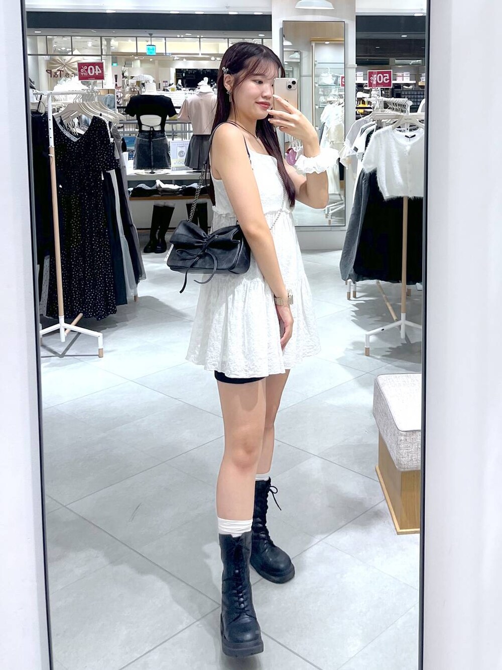 グレー系のショルダーバッグ、ホワイト系のワンピース、ブラック系のブーツを着用したレディースの夏コーディネートの9枚目の写真