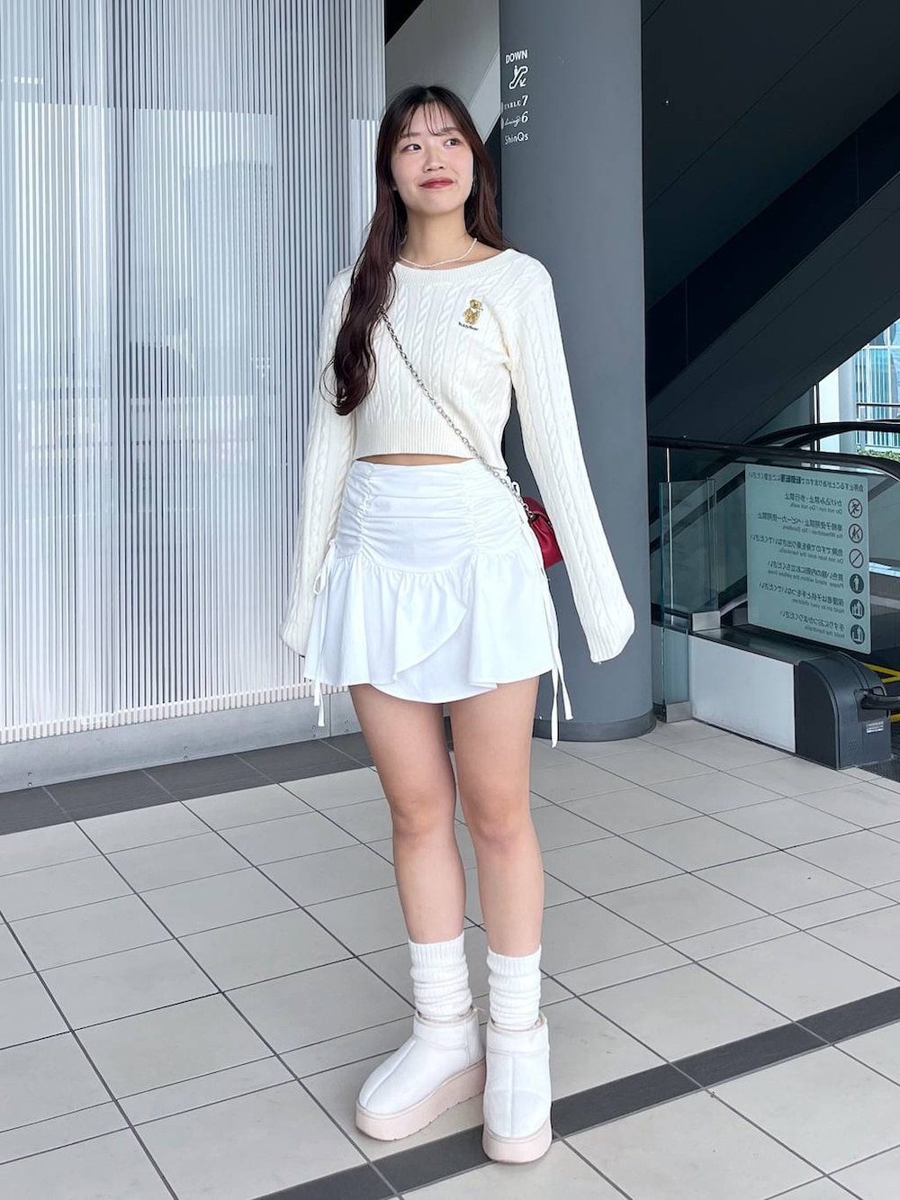 ホワイト系のTシャツ/カットソー、レッド系のショルダーバッグ、ホワイト系のブーツを着用したレディースの冬コーディネートの5枚目の写真