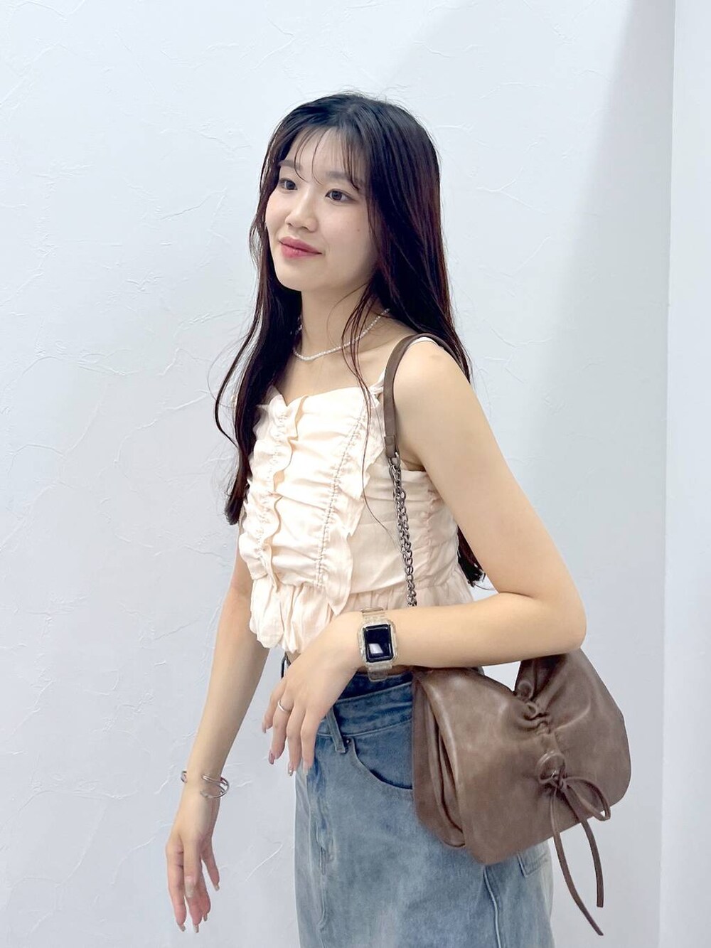 ブラウン系のショルダーバッグ、ホワイト系のキャミソール、ブルー系のデニムスカートを着用したレディースの夏コーディネートの3枚目の写真