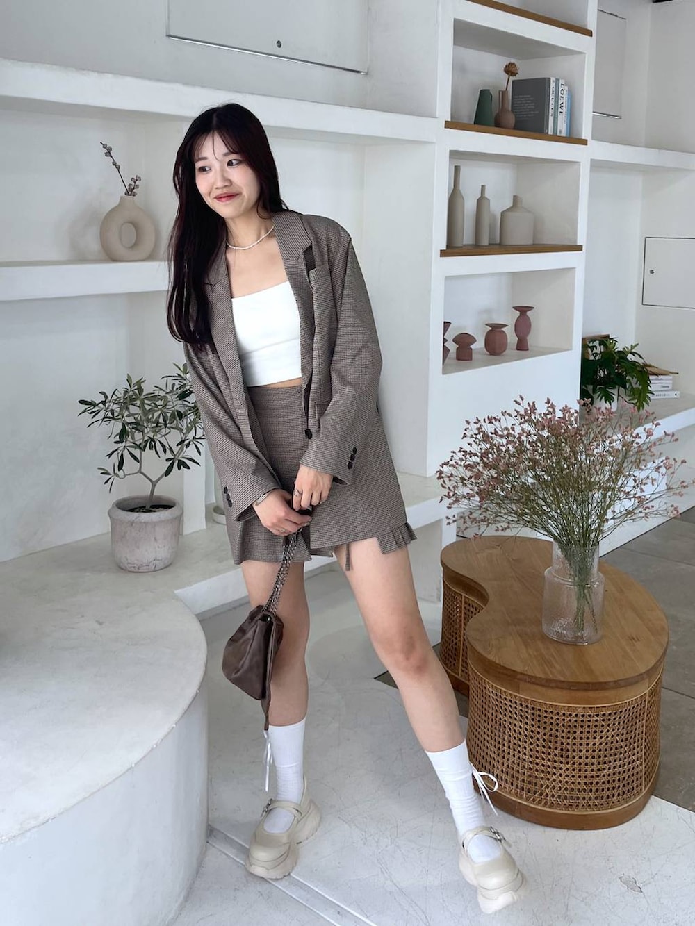 ブラウン系のショルダーバッグ、ホワイト系のキャミソール、ベージュ系のテーラードジャケットを着用したレディースの秋コーディネートの2枚目の写真