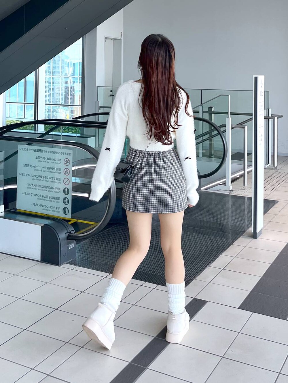 ブラック系のスカート、ホワイト系のニット/セーター、ブラック系のショルダーバッグを着用したレディースの秋コーディネートの6枚目の写真