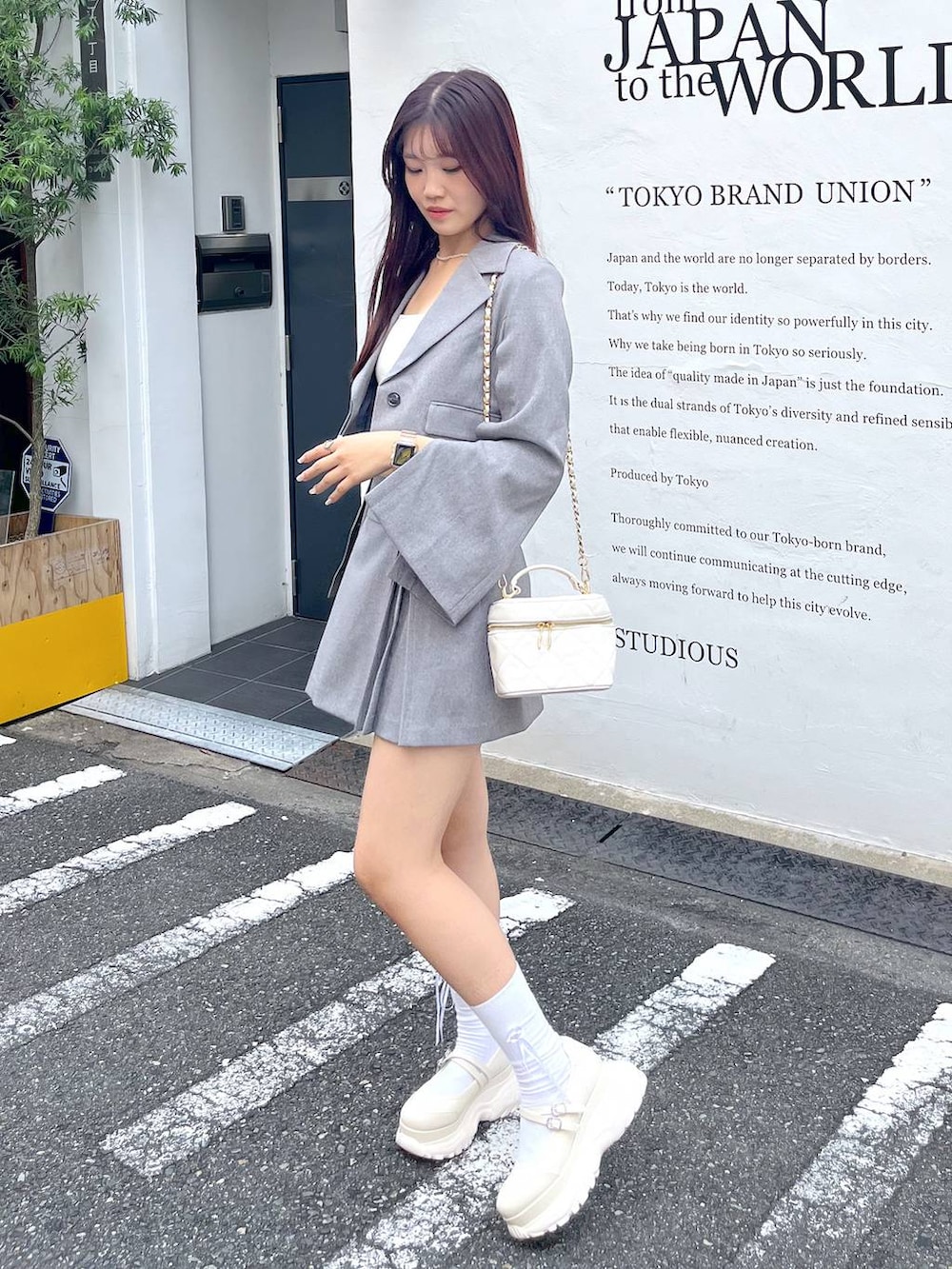 グレー系のテーラードジャケット、ホワイト系のショルダーバッグ、ホワイト系のキャミソールを着用したレディースの夏コーディネートの6枚目の写真