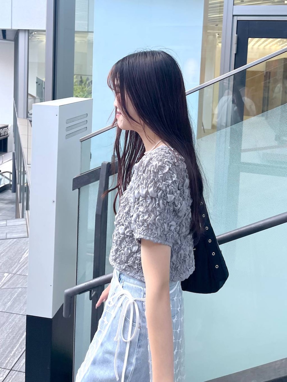 シルバー系のサンダル、ホワイト系のキャミソール、ブルー系のデニムパンツを着用したレディースの夏コーディネートの2枚目の写真