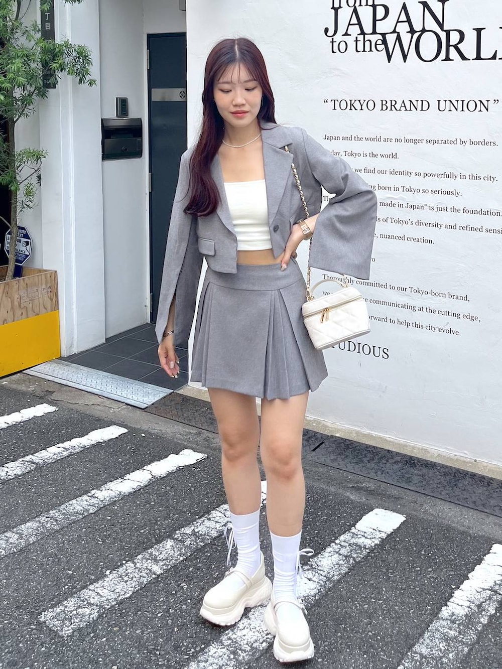 グレー系のテーラードジャケット、ホワイト系のショルダーバッグ、ホワイト系のキャミソールを着用したレディースの夏コーディネートの3枚目の写真