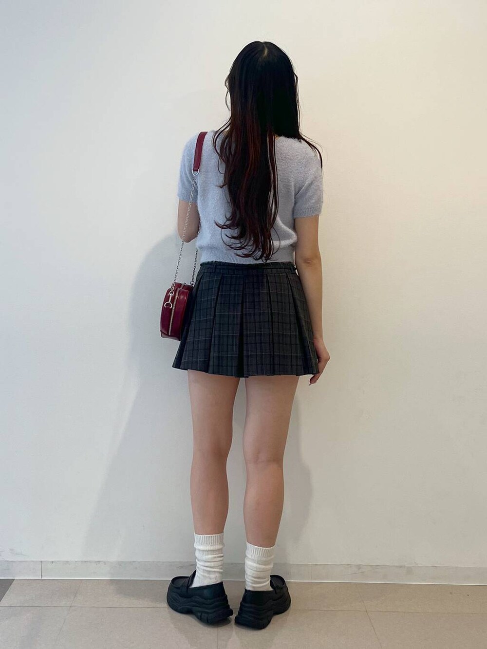 ブラック系のローファー、グレー系のスカート、レッド系のショルダーバッグを着用したレディースの春コーディネートの4枚目の写真