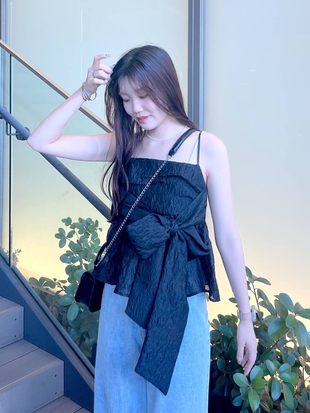 シルバー系のサンダル、ブラック系のショルダーバッグ、ホワイト系のキャミソールを着用したレディースの夏コーディネートの4枚目の写真