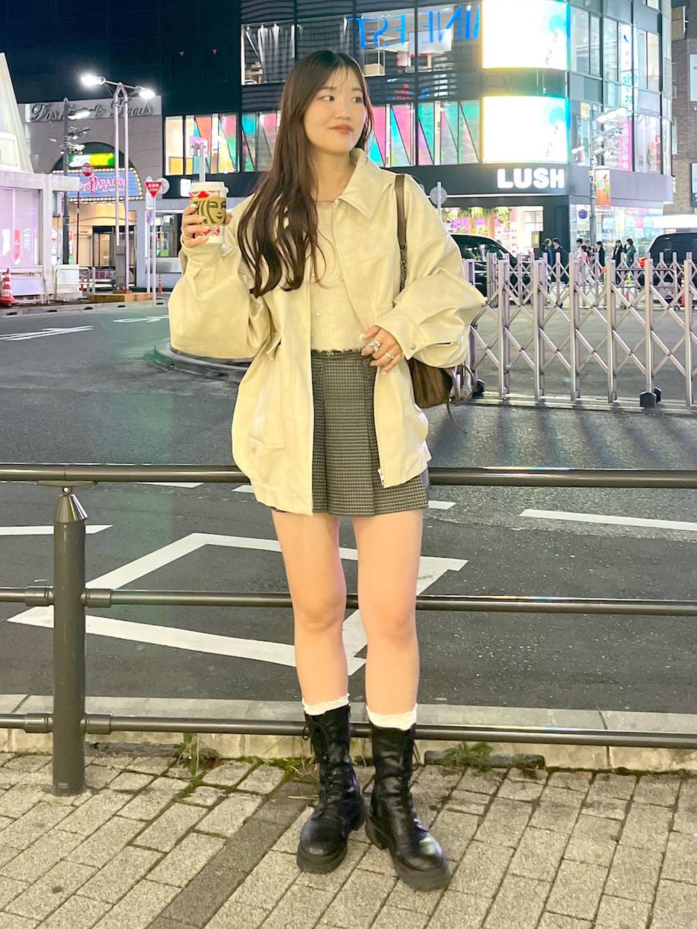 ブラウン系のショルダーバッグ、ベージュ系のスカート、ブラック系のブーツを着用したレディースの秋コーディネートの4枚目の写真