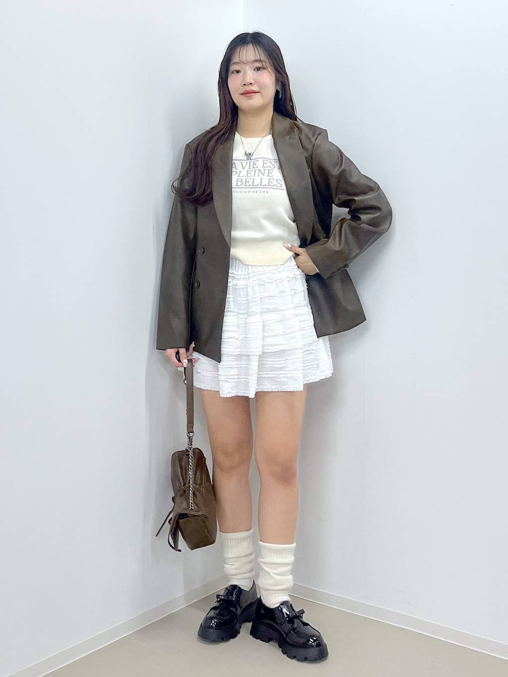 ホワイト系のキャミソール、ブラック系のドレスシューズ、ブラウン系のテーラードジャケットを着用したレディースの春コーディネートの3枚目の写真