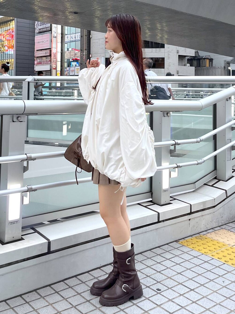 ブラウン系のショルダーバッグ、ブラウン系のブーツ、ホワイト系のキャミソールを着用したレディースの秋コーディネートの5枚目の写真