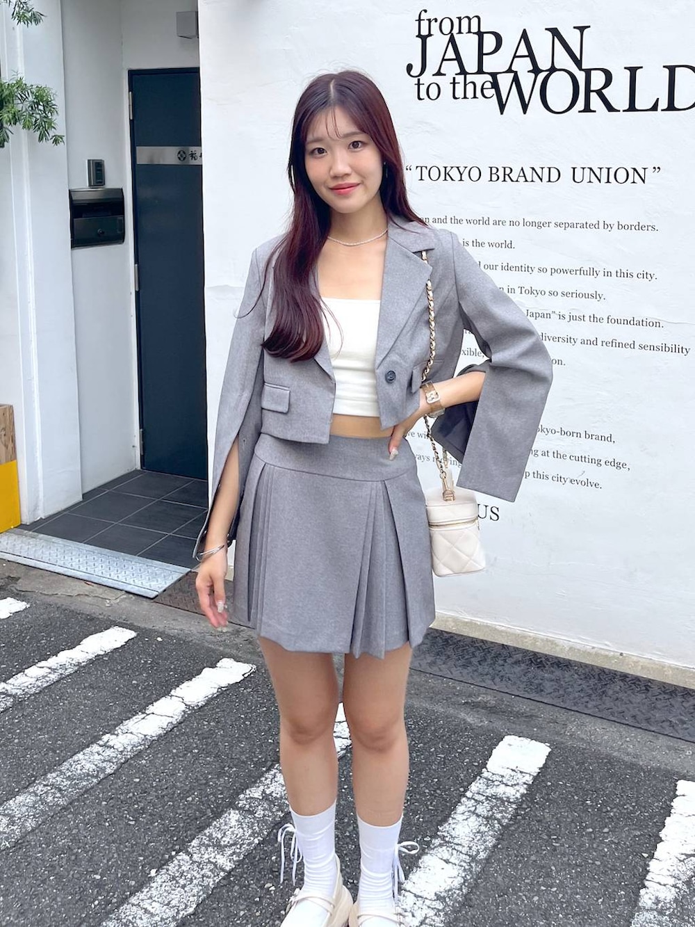 グレー系のテーラードジャケット、ホワイト系のショルダーバッグ、ホワイト系のキャミソールを着用したレディースの夏コーディネートの9枚目の写真