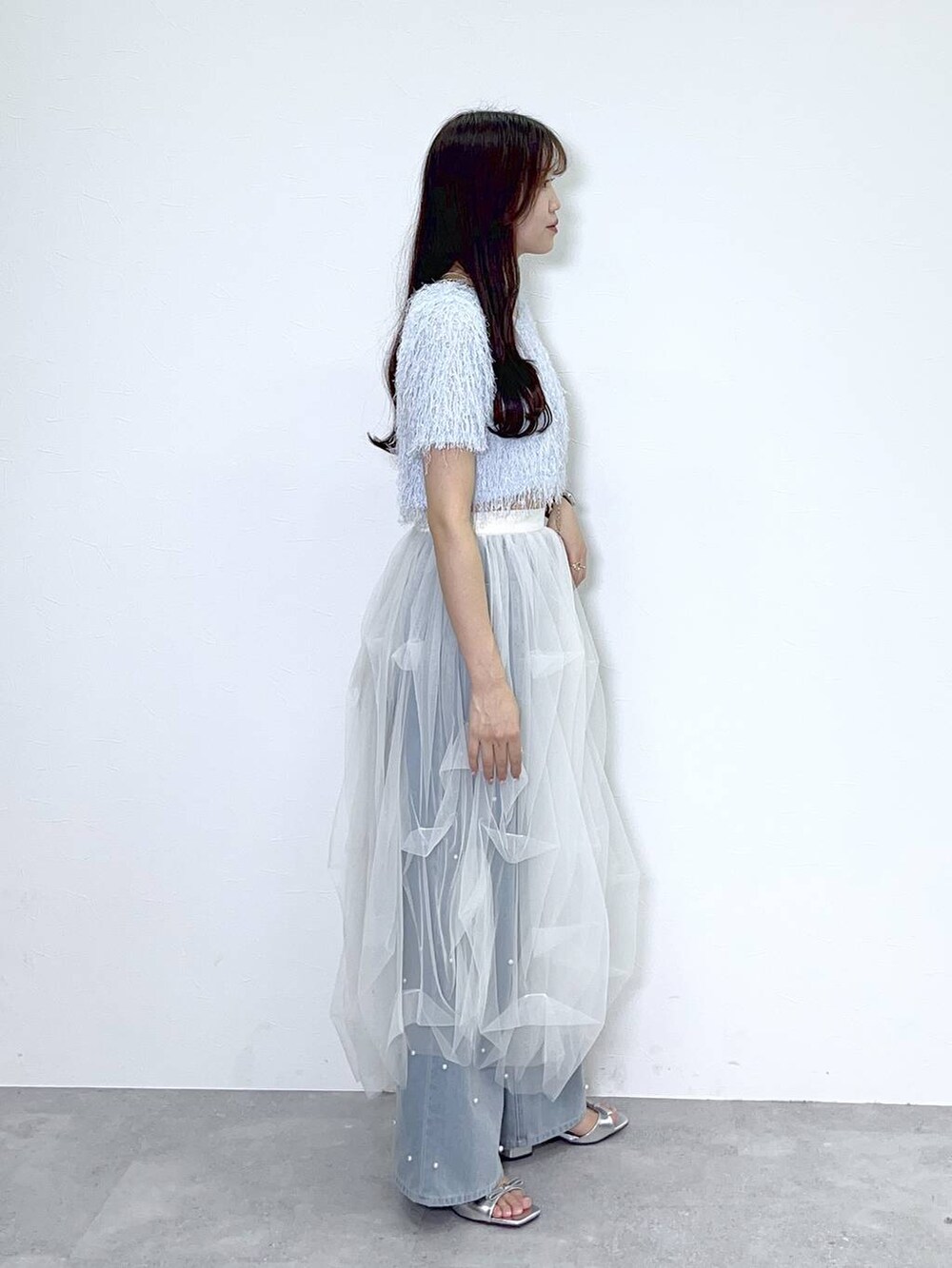 シルバー系のショルダーバッグ、ブルー系のデニムパンツ、ホワイト系のキャミソールを着用したレディースの春コーディネートの5枚目の写真