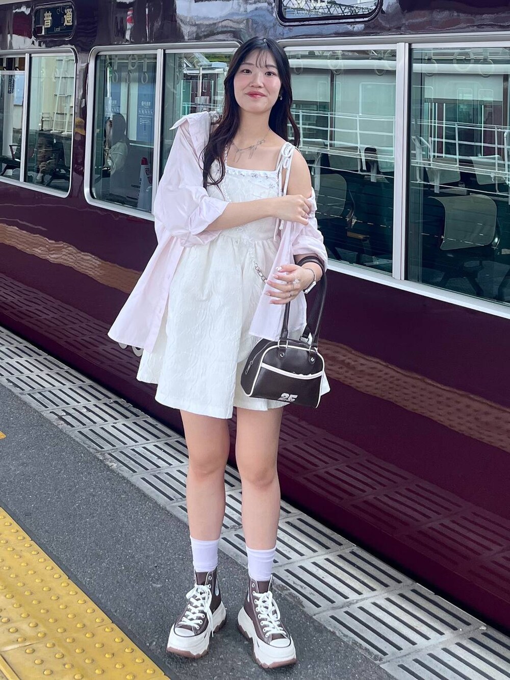 ホワイト系のワンピース、ホワイト系のカーディガン/ボレロ、ブラウン系のボストンバッグを着用したレディースの春コーディネートの2枚目の写真