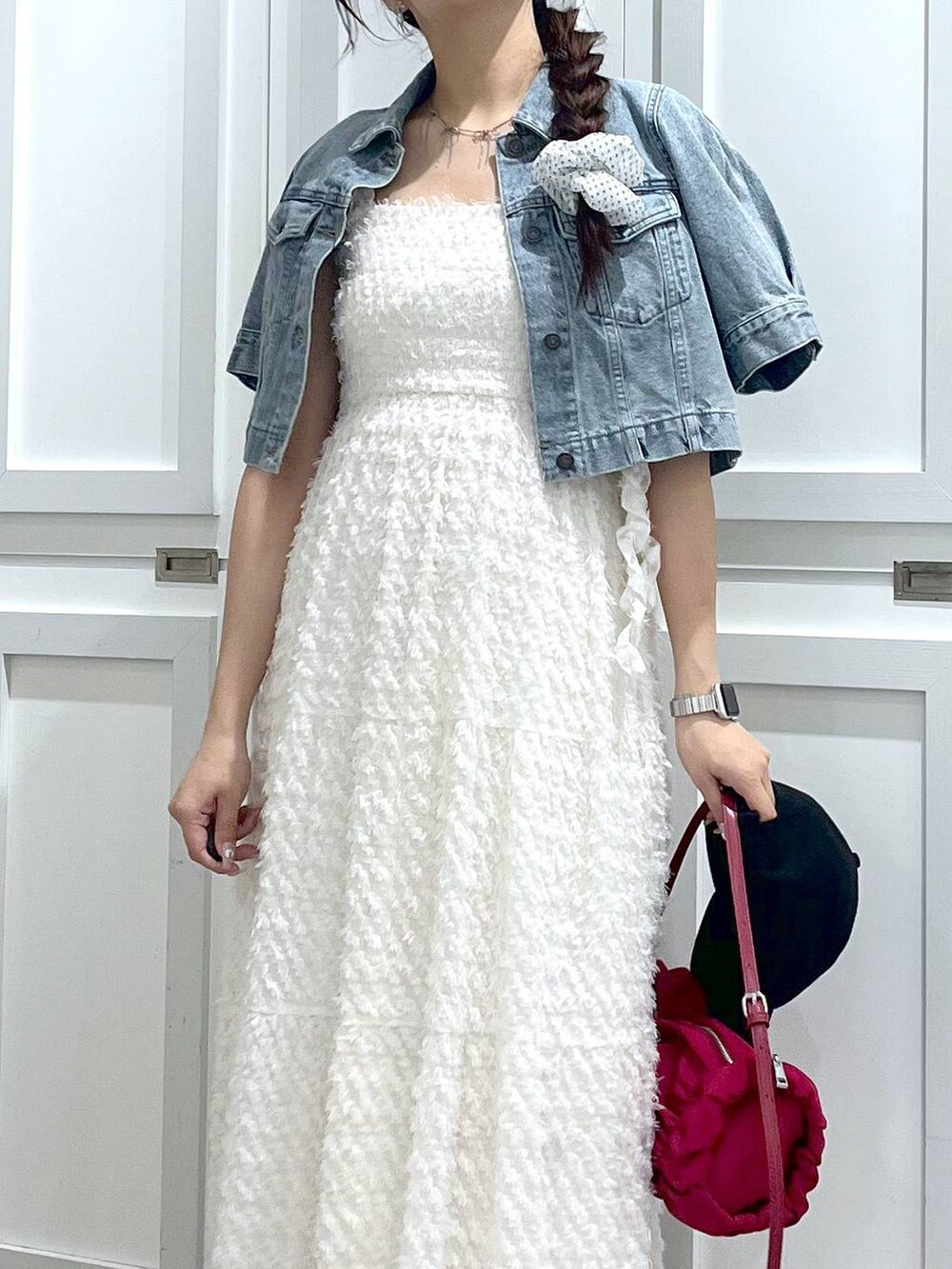 シルバー系のサンダル、ブルー系のデニムジャケット、ホワイト系のワンピースを着用したレディースの春コーディネートの4枚目の写真