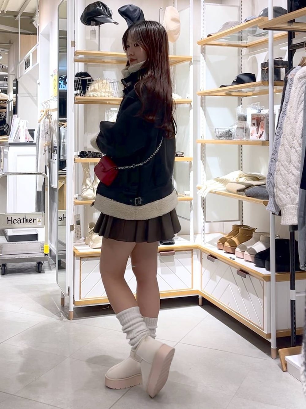 ブラウン系のスカート、ホワイト系のニット/セーター、ホワイト系のブーツを着用したレディースの冬コーディネートの3枚目の写真