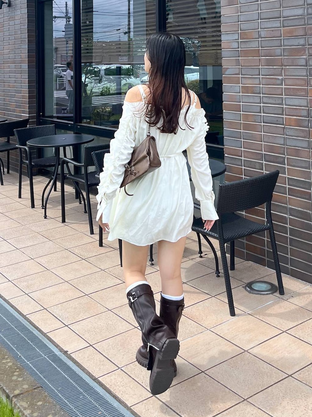 ブラウン系のショルダーバッグ、ブラウン系のブーツ、ホワイト系のキャミソールを着用したレディースの夏コーディネートの2枚目の写真