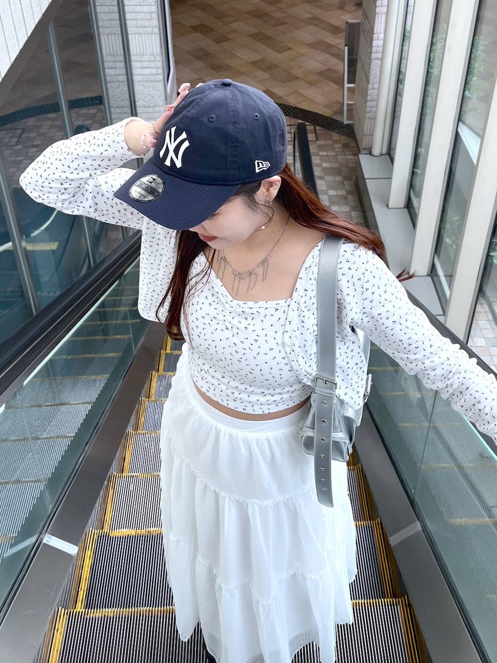 シルバー系のショルダーバッグ、ホワイト系のスカート、ホワイト系のアンサンブルを着用したレディースの春コーディネートの5枚目の写真