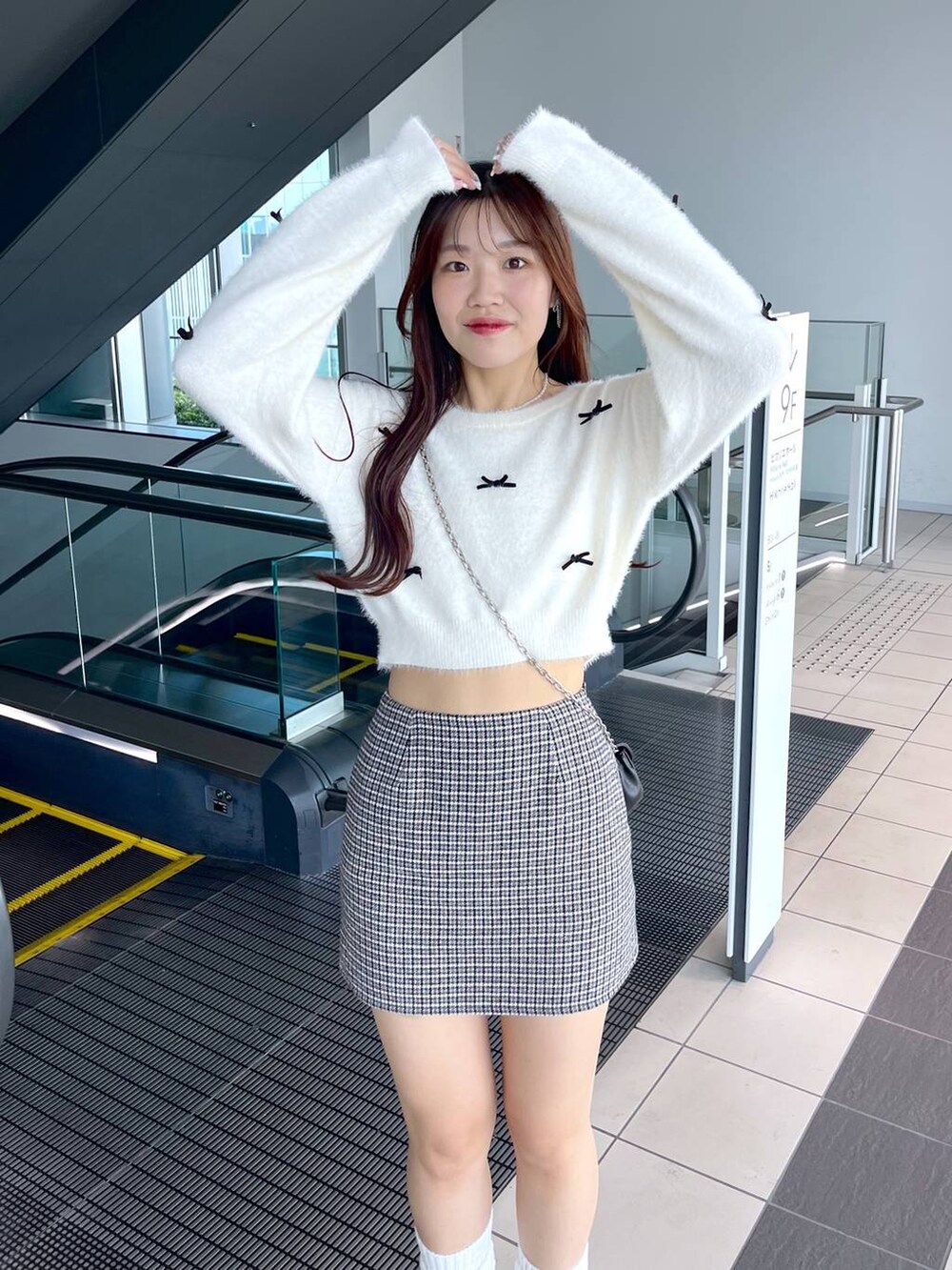 ブラック系のスカート、ホワイト系のニット/セーター、ブラック系のショルダーバッグを着用したレディースの秋コーディネートの4枚目の写真