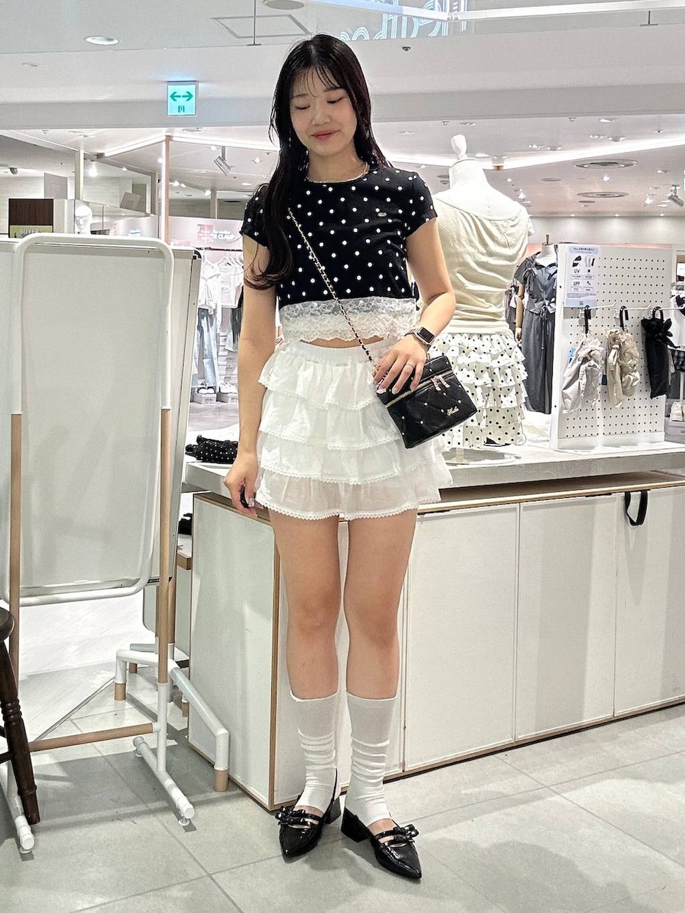 ブラック系のショルダーバッグ、ブラック系のパンプス、ホワイト系のチューブトップを着用したレディースの夏コーディネートの2枚目の写真