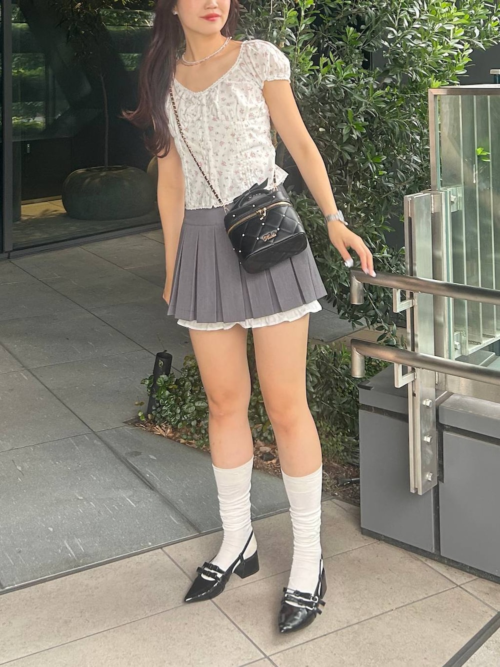 ブラック系のショルダーバッグ、グレー系のスカート、ブラック系のパンプスを着用したレディースの夏コーディネートの7枚目の写真