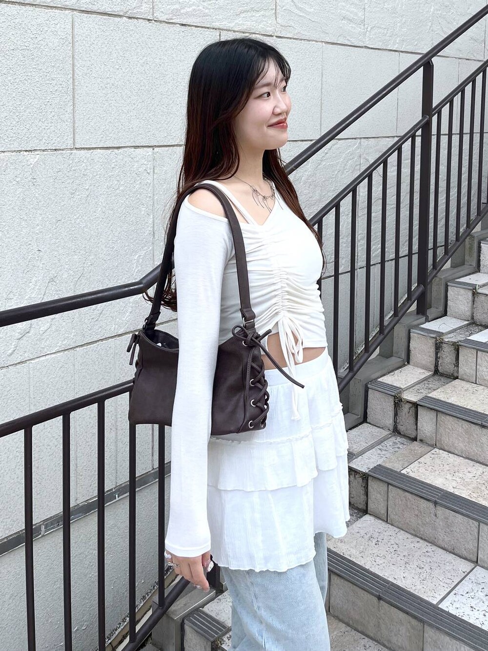 ブルー系のデニムパンツ、ホワイト系のキャミソール、ホワイト系のスカートを着用したレディースの春コーディネートの3枚目の写真