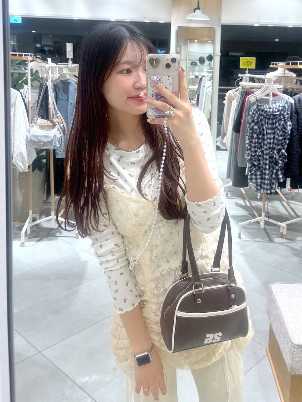 ベージュ系のワンピース、ブラウン系のボストンバッグ、ホワイト系のスマホグッズを着用したレディースの春コーディネートの2枚目の写真