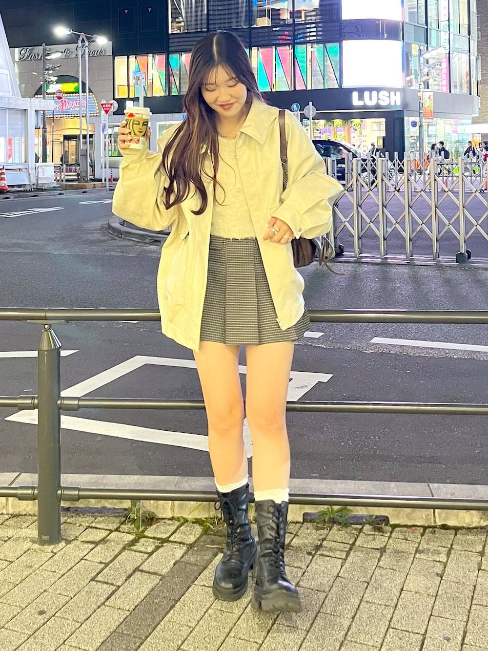 ブラウン系のショルダーバッグ、ベージュ系のスカート、ブラック系のブーツを着用したレディースの秋コーディネートの7枚目の写真