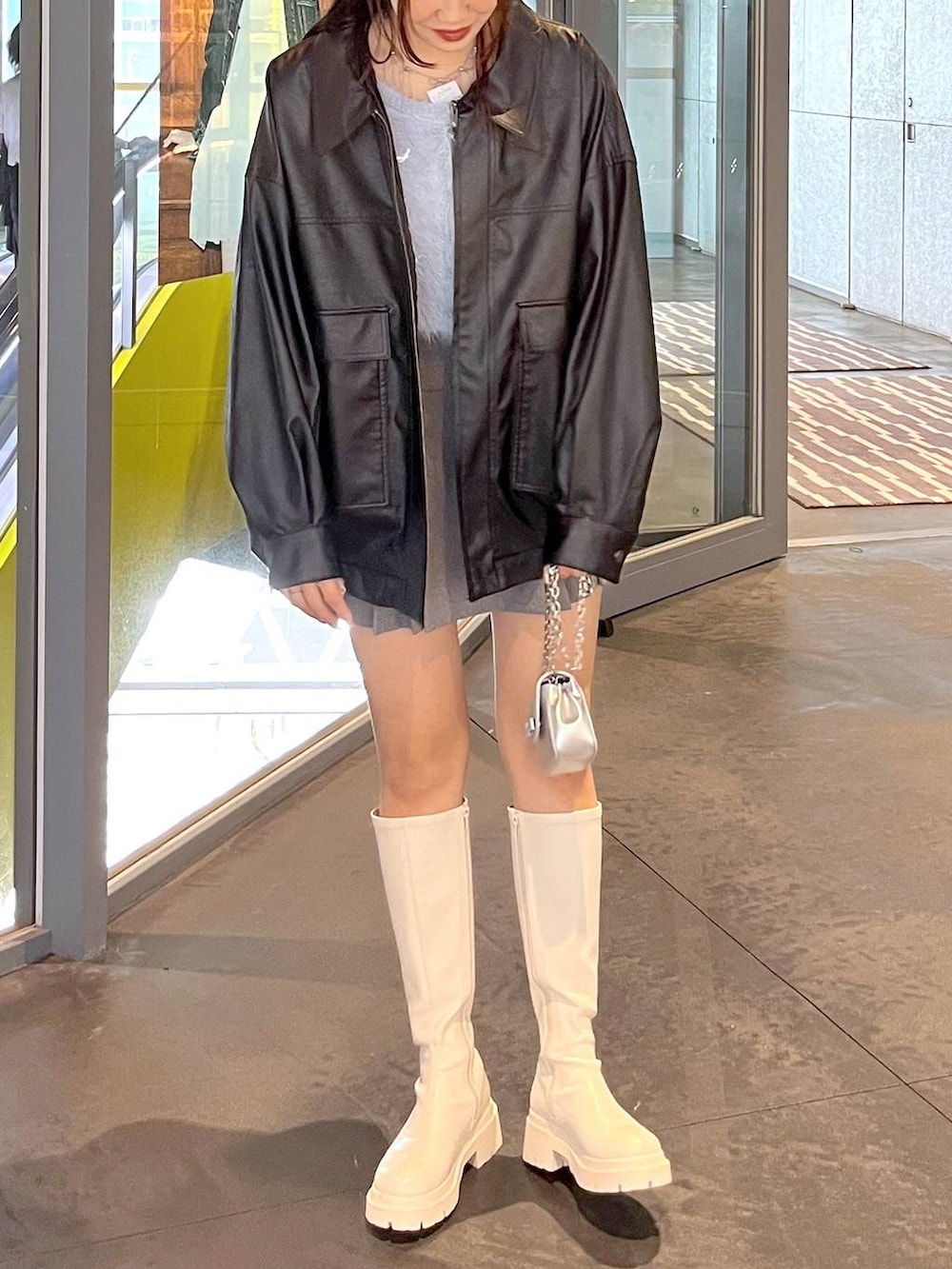 グレー系のスカート、ホワイト系のブーツ、ブラック系のブルゾンを着用したレディースの秋コーディネートの9枚目の写真
