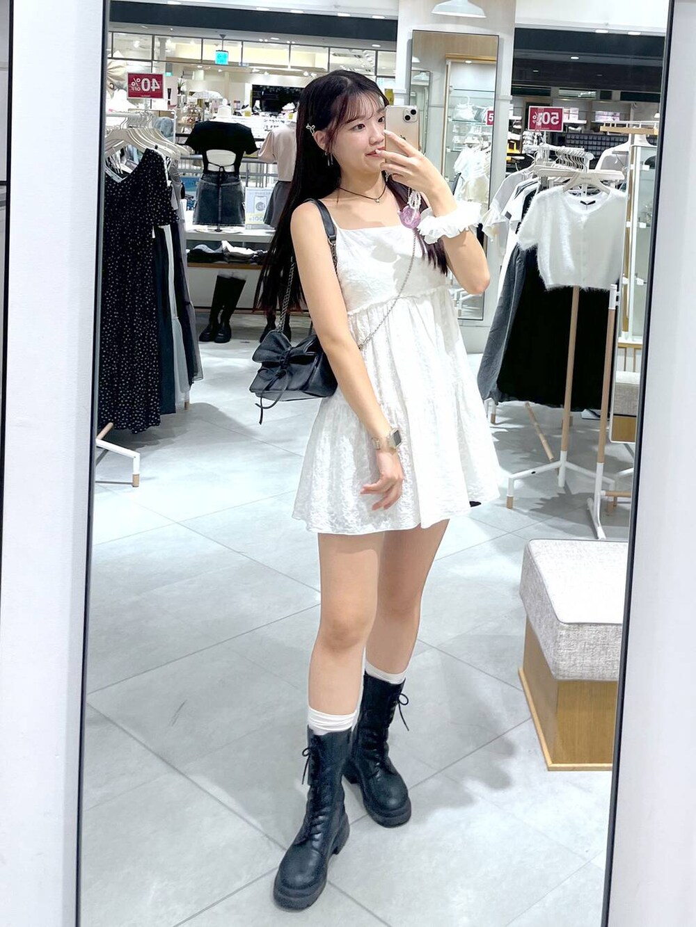 グレー系のショルダーバッグ、ホワイト系のワンピース、ブラック系のブーツを着用したレディースの夏コーディネートの7枚目の写真