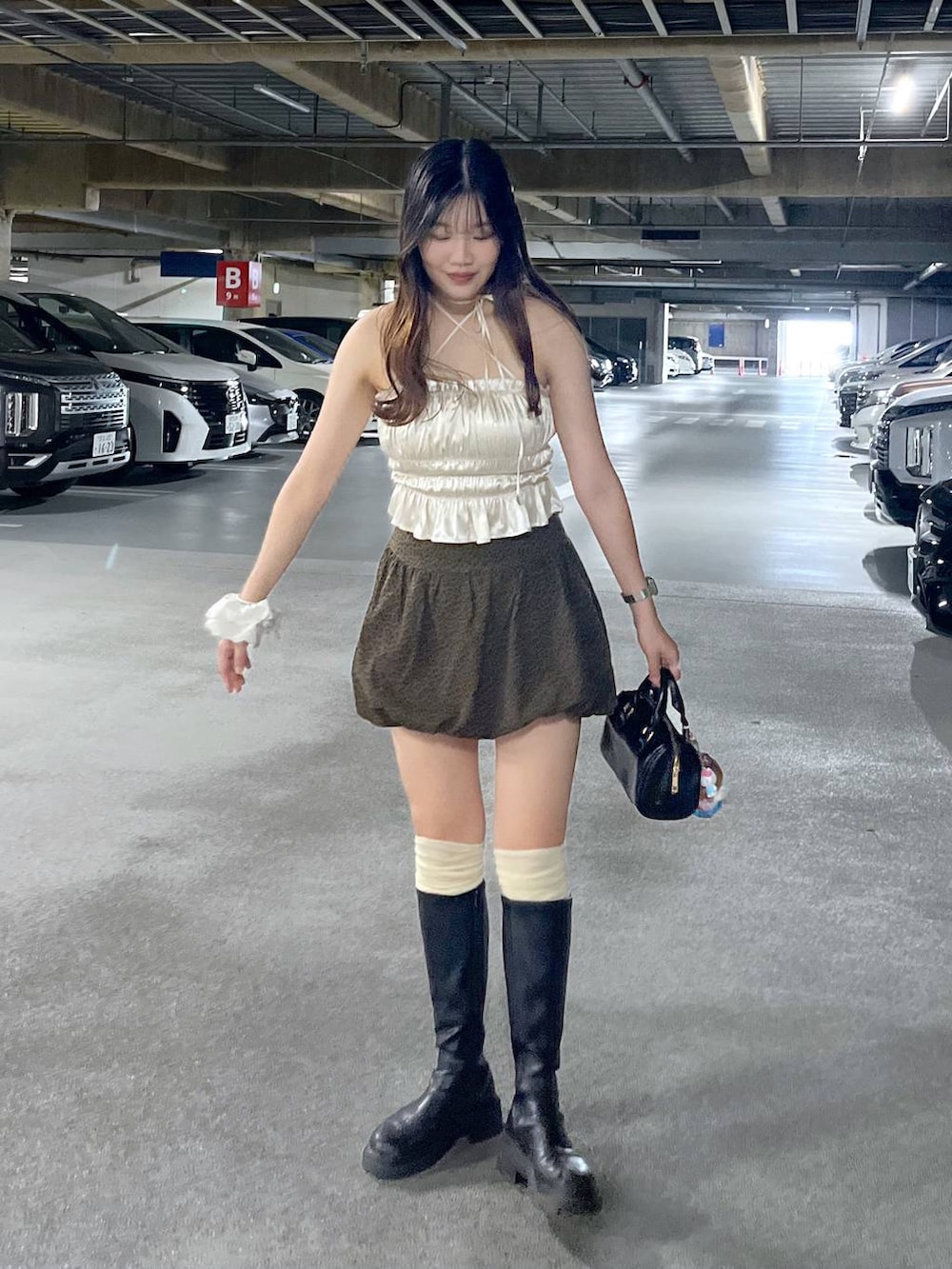 ブラック系のブーツ、ホワイト系のキャミソール、ブラウン系のスカートを着用したレディースの夏コーディネートの4枚目の写真