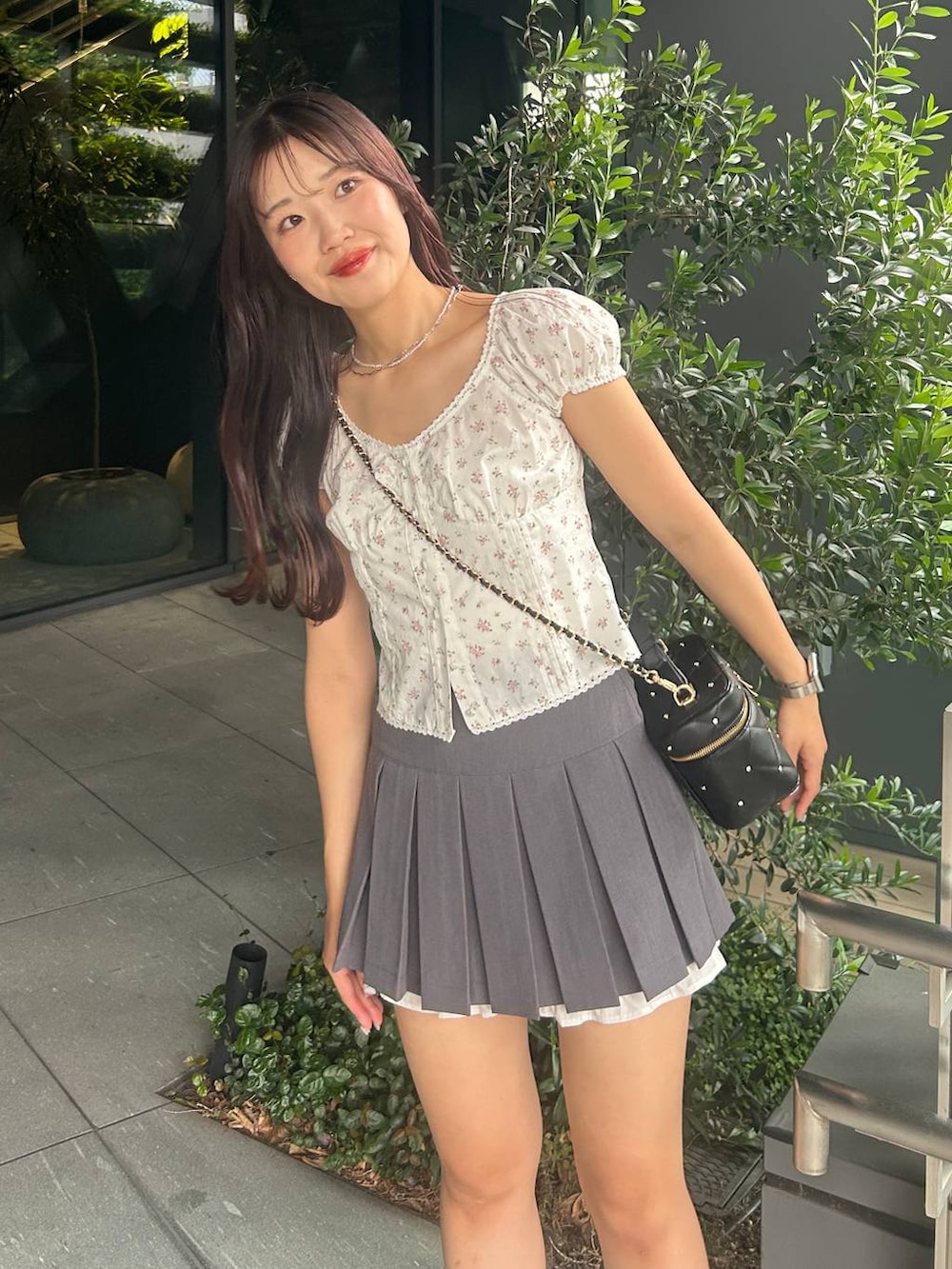 ブラック系のショルダーバッグ、グレー系のスカート、ブラック系のパンプスを着用したレディースの夏コーディネートの2枚目の写真