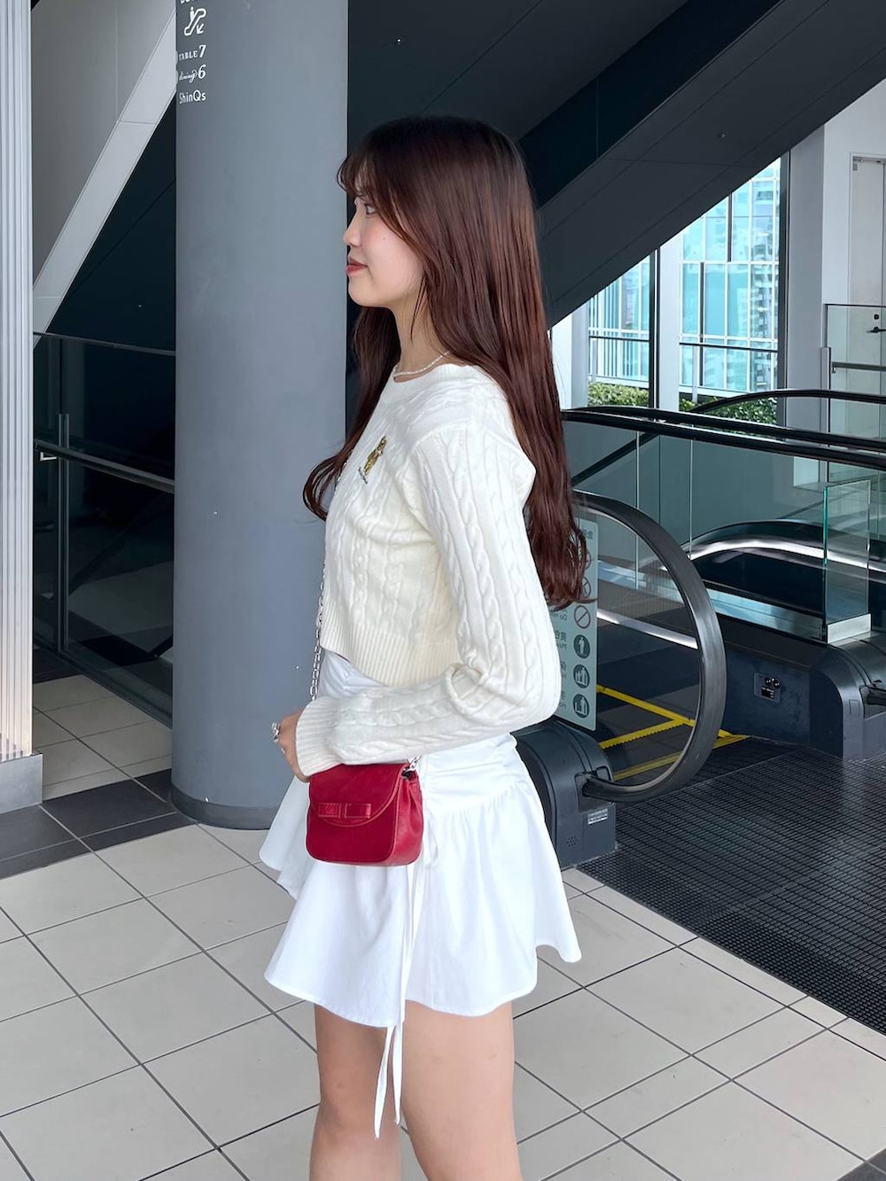 ホワイト系のTシャツ/カットソー、レッド系のショルダーバッグ、ホワイト系のブーツを着用したレディースの冬コーディネートの3枚目の写真